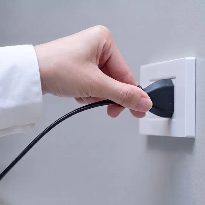 Hand connecting an appliance to a wall outlet