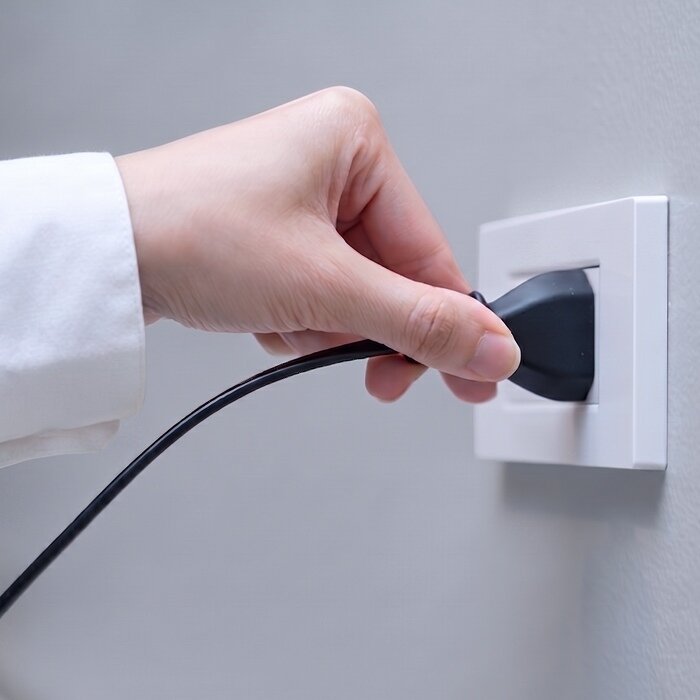 Hand plugging an appliance into a wall outlet